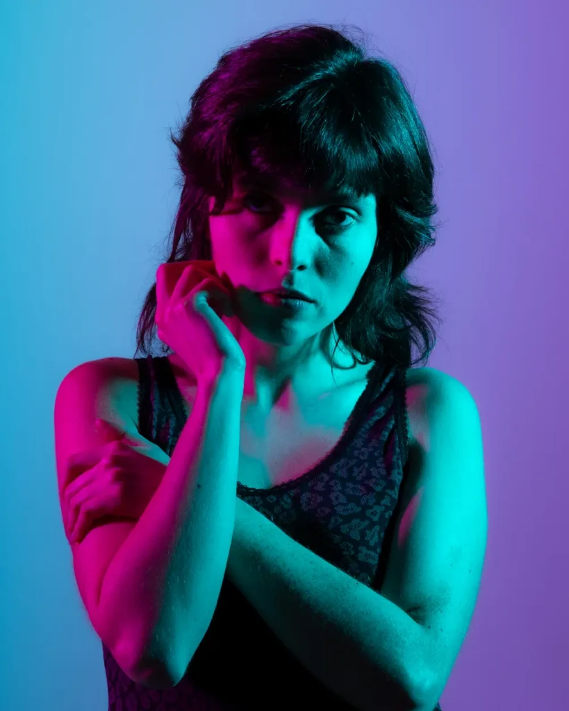 Portrait éditorial féminin avec éclairage gélatines violet et cyan sur fond dégradé bleu violet