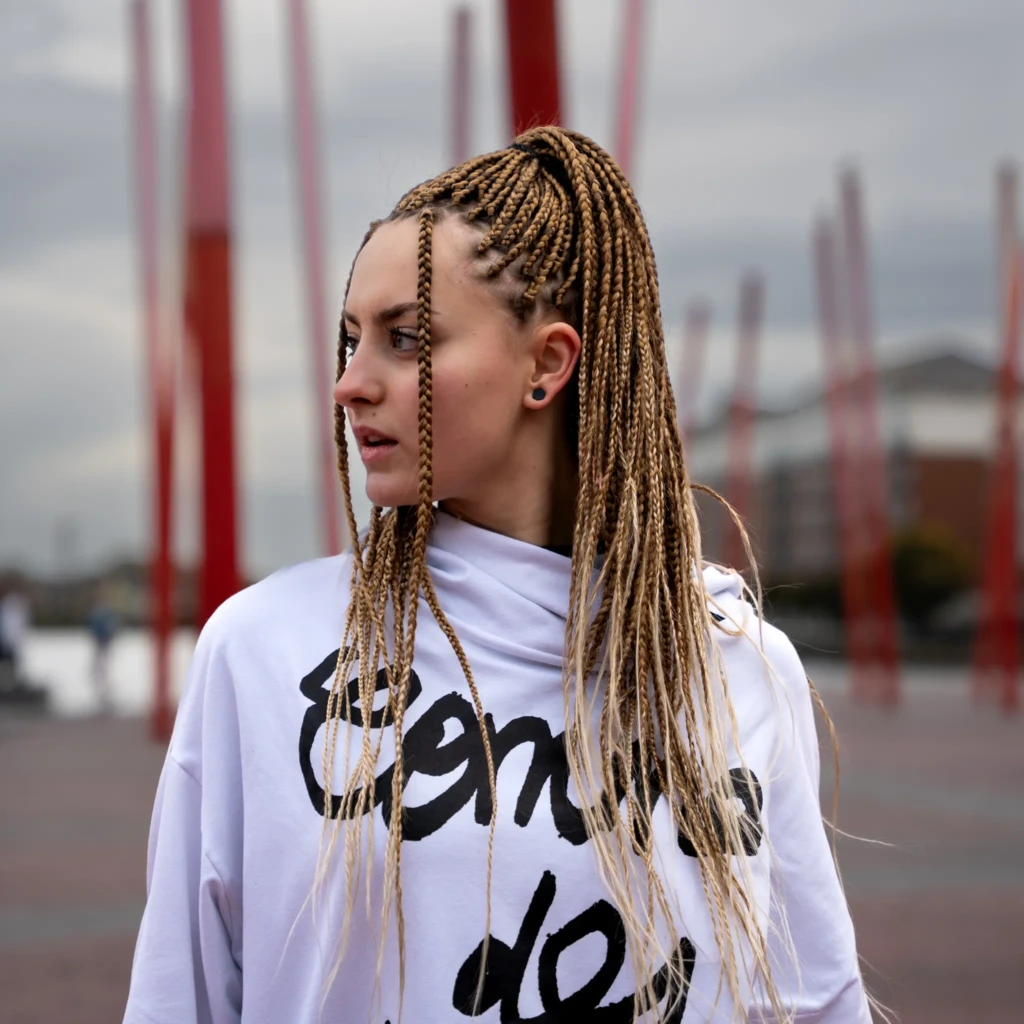 Portrait éditorial d'une jeune femme aux tresses blondes en extérieur, lumière naturelle