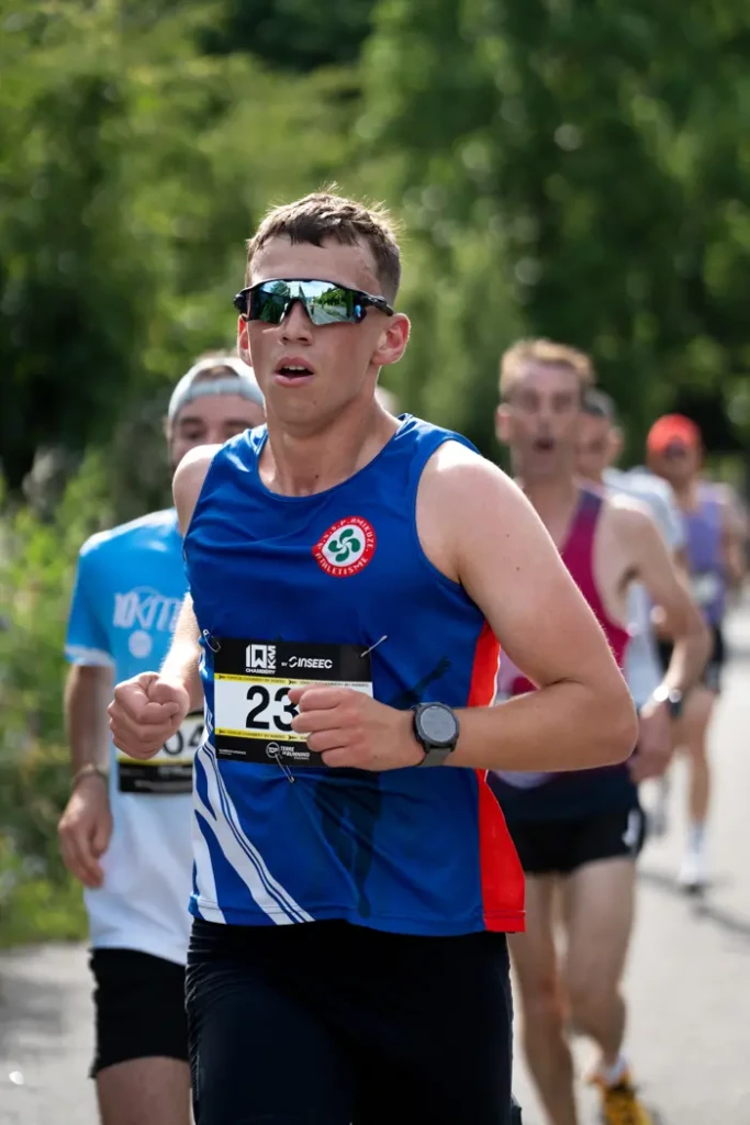 Jeune coureur en maillot bleu de club athlétisme en plein effort lors du 10 km de Chambéry, photographie sportive